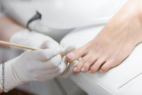 Specialist in beauty salon making french pedicure for female client.