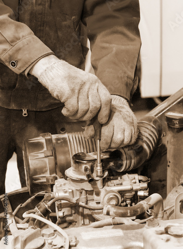 Measuring valve clearance with tappet feeler gauge set. Sepia photo.