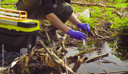 Close up hands of scientist ecologist in the forest taking sample of water in the test tube