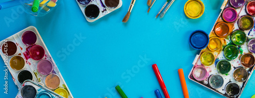 Watercolor paints, artistic brushes,pens accessories for an artist long drawing on a blue background with copy space flatlay top view from above long banner