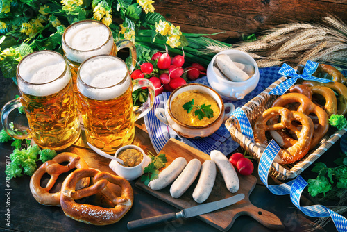 Bavarian sausages with pretzels, sweet mustard and beer mugs on rustic wooden table