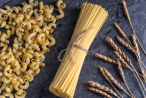 Uncooked italian pasta spaghetti and cavatappi with spikelets of durum wheat. Concept of the composition of food design.