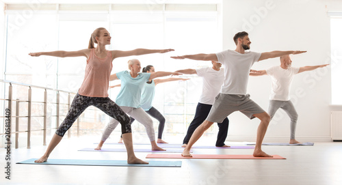 Group of people in sportswear practicing yoga indoors
