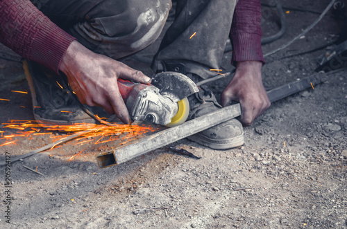 Manual cutting metal pipe with a circular saw. Hands, worker, flying sparks.
