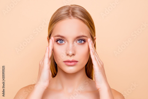 Portrait of pretty, charming, natural, pure, cute, healthy girl with smooth soft skin thinking about tightening near eyes, ready for plastic surgery treatment, isolated on beige background