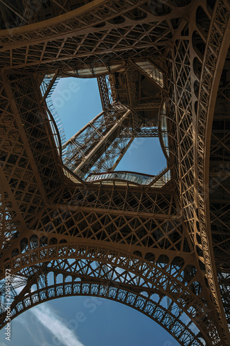 Bottom view of Eiffel Tower made in iron and Art Nouveau style, with sunny blue sky in Paris. Known as the “City of Light”, is one of the most impressive world’s cultural center. Northern France.