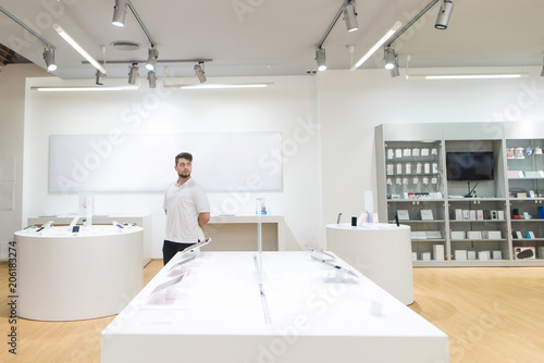 Man walks on a light modern technology store. Choosing gadgets in the electronics store. A modern tech shop with a stylish light interior.