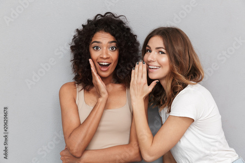 Portrait of two happy young women sharing secrets