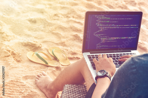 A programmer typing source codes at the beach on a sunny summer day. Studying, Working, Technology, Freelance Work Concept.