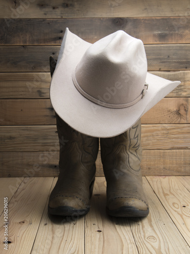 Cowboy boot and western hat on wooden background.