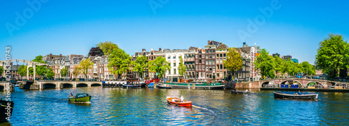 Amsterdam, May 7 2018 - view on the river Amstel filled with small boats and the Magere brug (skinny bridge) in the background on a summer day