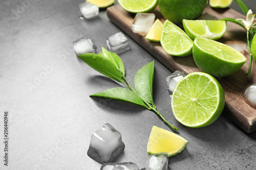 Composition with fresh ripe limes and ice cubes on gray background