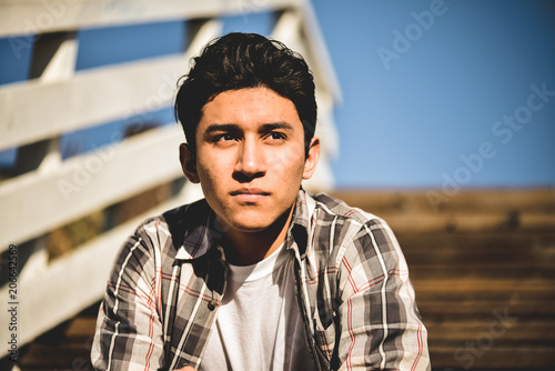 Young hispanic latino male looking off into the distance, serious facial expression 