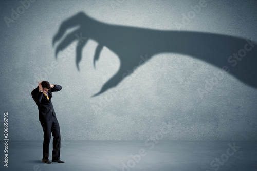 Business person afraid of a big monster claw shadow concept on background