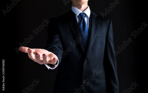 Man in a business suit holding his hand out and showing something