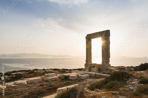 View over ruins of ancient marble doorway monument Portara at sunset in Naxos, Greece.