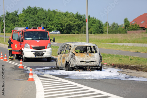 Spalony samochód osobowy na ulicy, pożar ugaszony przez straż pożarną.