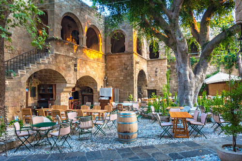 Peaceful sitting under tree among medieval buildings in City of Rhodes (Rhodes, Greece)