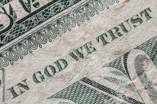 A detail of a one dollar bill. We can read the famous sentence "in god we trust". It is an old note..