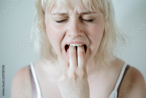 Portrait of young blond woman, annoyed, frustrated fed up sticking her finger in her throat. Mental disorders bulimia, addiction.