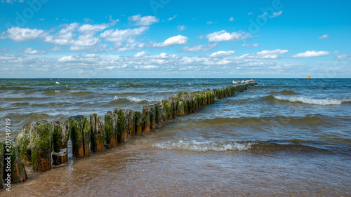 spokojne morze Bałtyckie zalewa słoną wodą drewniane pale ochronne. Międzyzdroje, Polska