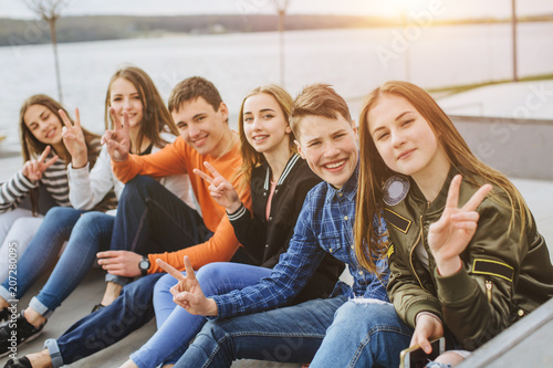 Summer holidays and teenage concept - group of smiling teenagers with skateboard hanging out outside.