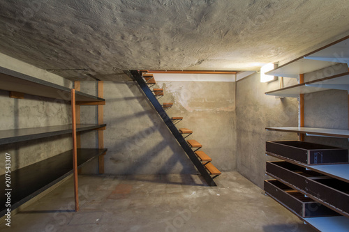 empty basement in abandoned old industrial building with little light and a wooden stairs