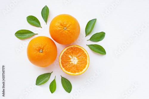 Fresh orange citrus fruit with leaves on white wooden background.