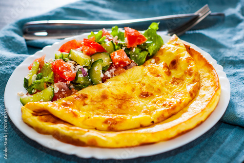 Omelet with vegetable salad in white plate on table