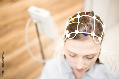 Young female with electrode equipment on her head having clinical test in hospital