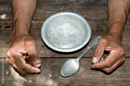 hands the poor old man's and empty bowl on wood background. The concept of hunger or poverty. Selective focus. Poverty in retirement.Homeless. Alms