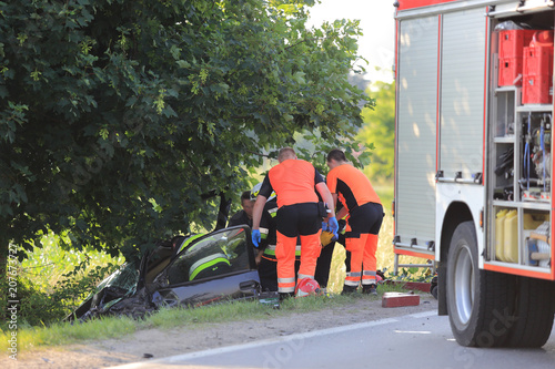 Wypadek samochodu, ratownicy pogotowia i strażacy ratują kierowcę z rozbitego auta.