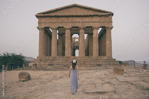 Young woman with hat backgards in Agrigento Temple at summer