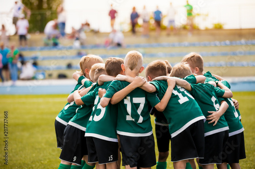 Young football soccer players in sportswear. Young sports team with football coach. Pep talk with coach before the final match. Soccer school tournament
