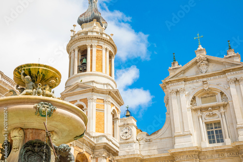 Loreto basilica in sunny day, fountain and tower in Loreto, Italy