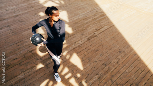 Fitness woman with medicine ball stretching and warming up outdoors 