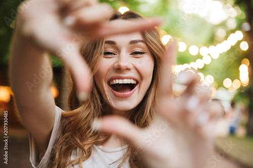 Close up of happy young girl showing frame with fingers