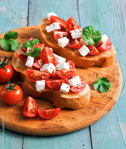 Bruschetta with tomato and cheese. Italian snack. Bruschetta on a blue wooden background. Selective focus.