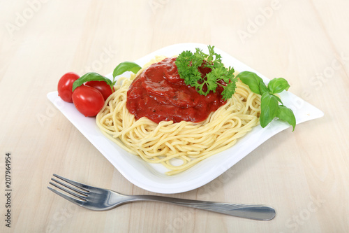 Spagetti z sosem bolońskim serem, pomidorami i zielonymi listkami bazyli i pietruszką.