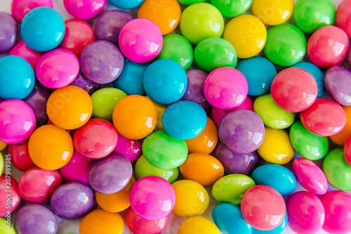 Pile of colorful sweet candy chocolates coated on white paper. colourful collection background