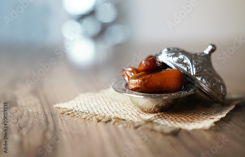 Fresh fruit dates in a silver metal bowl on a piece of sackcloth on walnut wooden table