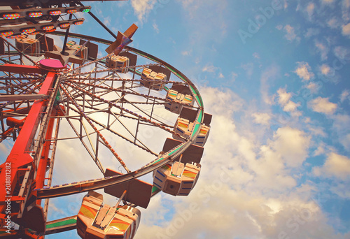 people riding rides and enjoying the summer atmosphere at a state fair at dusk toned with a retro vintage filter app or action