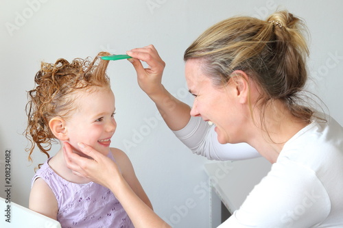 Mutter kämmt mit Läuasekamm Haare der Tochter