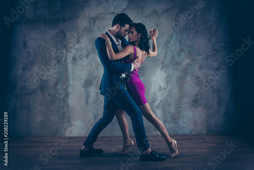 Pełnowymiarowy portret ciała uroczej atrakcyjnej pary stojącej blisko w pozycji tango taniec twarzą w twarz, czarująca dama w fioletowej obcisłej sukience panowie w smokingu na białym tle na szarym tle ruch