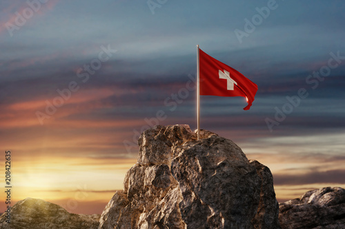Wehende Schweizer Fahne auf Bergspitze im wunderschönen Abendrot