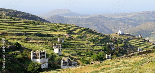 Panoramic spring landscape with famous traditional decorated dovecotes and hedges on the Tinos island and sea in the background, Greece