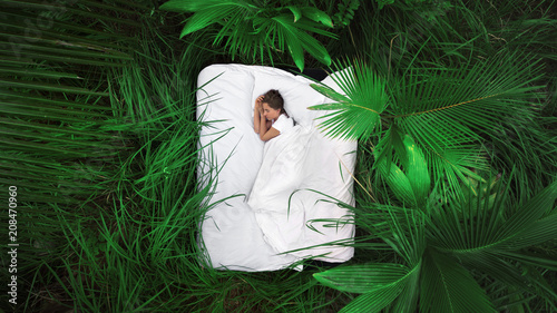 A hidden place. Sleeping woman in deep jungle forest lies on airbed,View from above