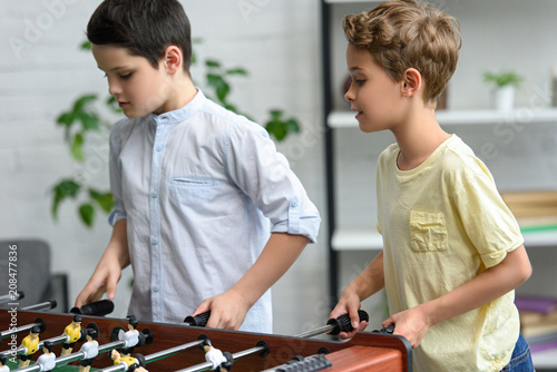 focused little boys playing table football together at home