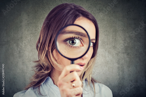 Curious woman looking through a magnifying glass