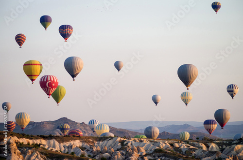 Hot air balloons at sunrise flying over Cappadocia, Turkey. A balloon with a flag of Turkey.
